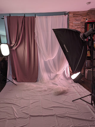 Behind-the-scenes view of Icon Provocateur's studio setup, featuring soft lighting and layered draped backdrops in mauve and white tulle.