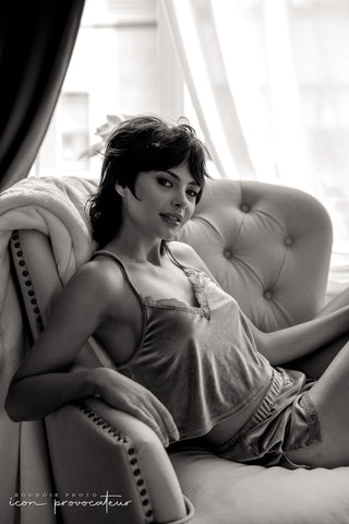Young woman lounging in a tufted armchair, backlit by soft window light, an effortlessly intimate lifestyle portrait by Icon Provocateur, Montreal’s inclusive luxury boudoir studio.