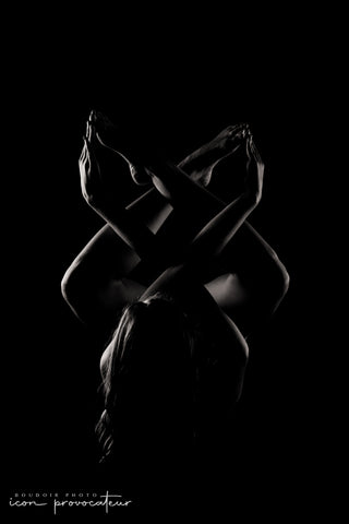 Artistic nude portrait of a woman lying on the floor with limbs gracefully crossed and silhouetted in dramatic low-key lighting, a bold and sculptural image by Icon Provocateur, Montreal’s inclusive luxury studio.